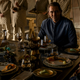 Three of Foundation's Empires sit around a rectangular table to eat a lavish meal. Left to right: Cooper Carter's Young Brother Dawn, Lee Pace's Brother Day, and Terrence Mann's Brother Dusk.